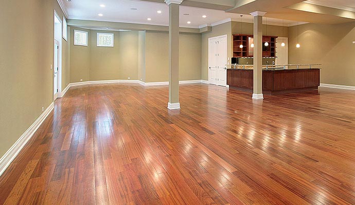 An expansive, open-concept finished basement featuring polished cherry-colored hardwood floors