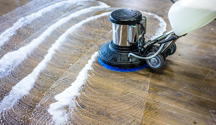 A floor cleaning machine restoring a wood floor by deep cleaning and renewing the surface without heavy sanding