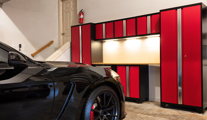 Organized garage with red cabinets and a black sports car