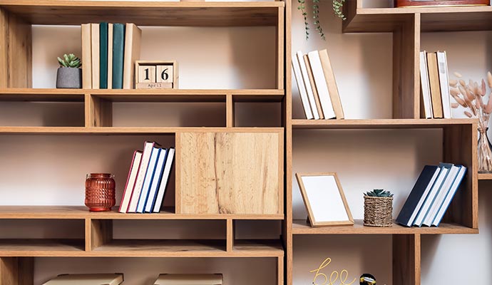 A section of a custom wooden bookcase filled with books, small plants, and home decor, showing a clean, organized style
